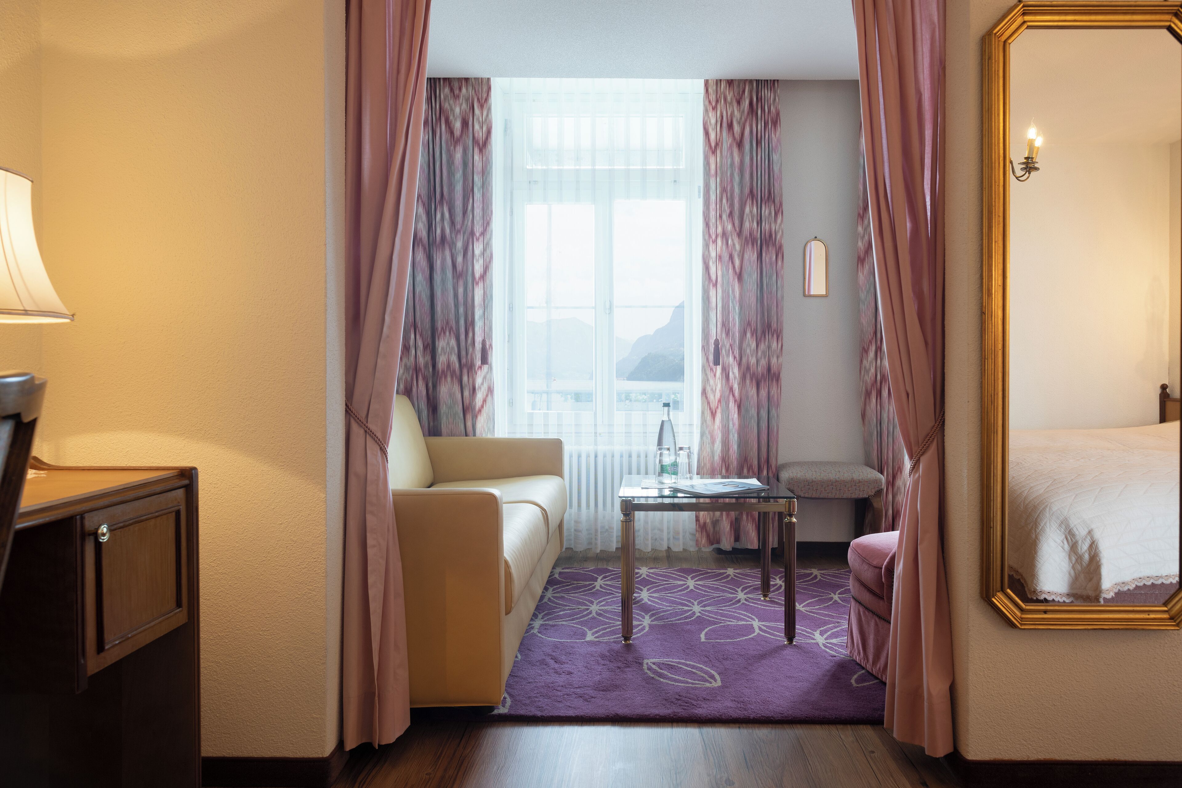 Una habitación de hotel con cama, sofá, una mesita y escritorio.