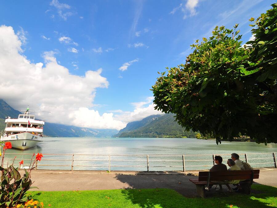 A lake with a boat, a bench, and a railing.