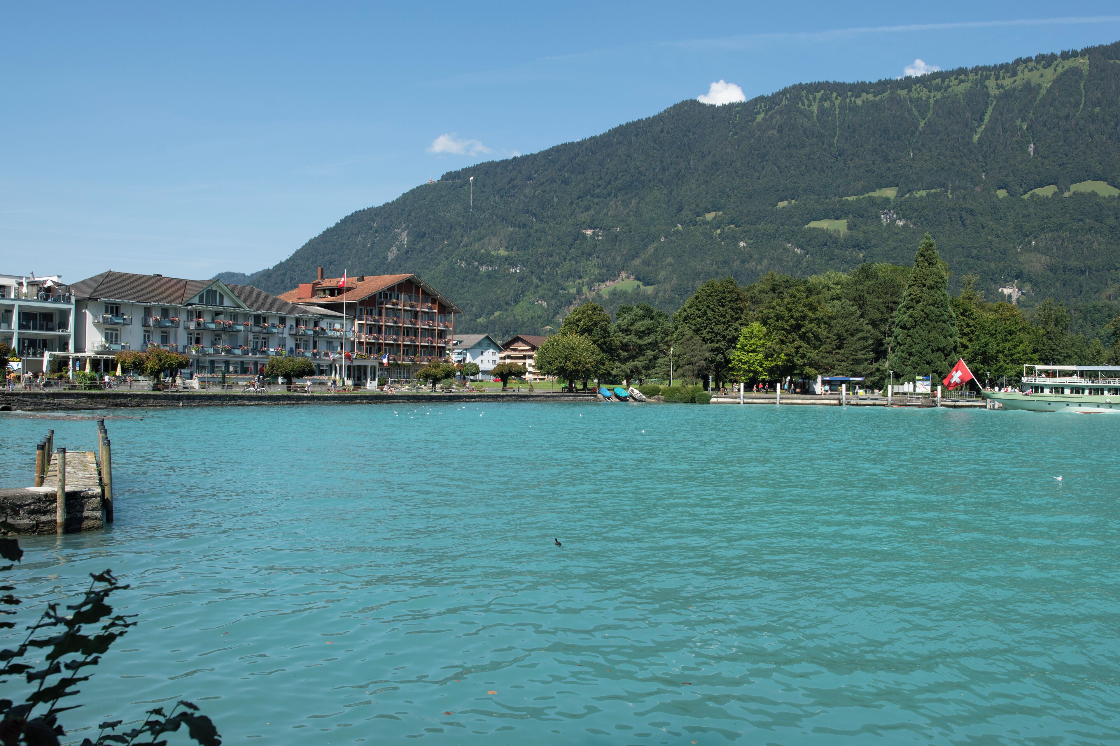 Un hôtel situé au bord de l’eau, doté de nombreux balcons, d’un quai et offrant une vue sur les montagnes.
