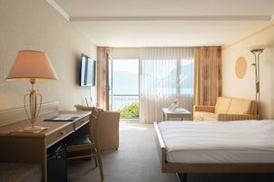 Habitación de hotel con cama, escritorio, silla y vistas al exterior.