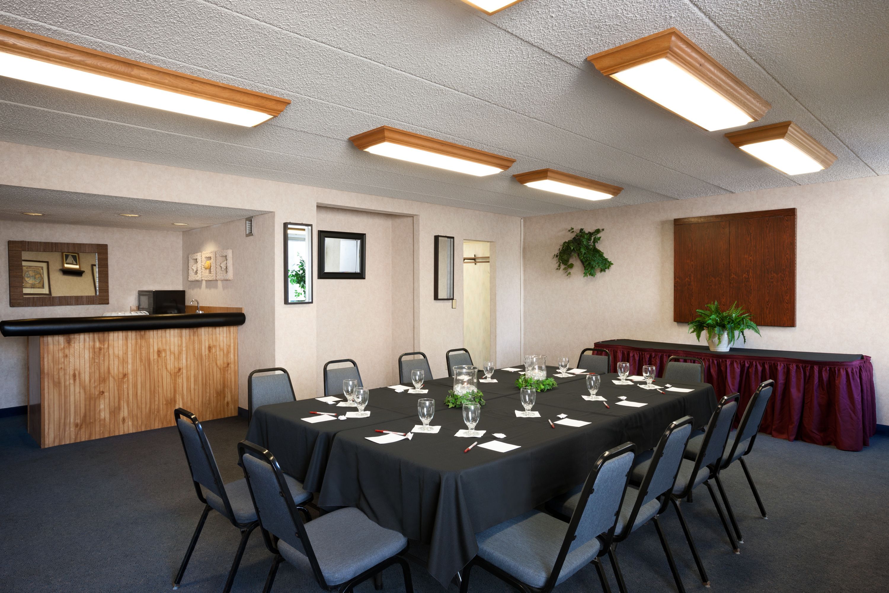 A conference room with a long table, chairs, a bar area, and framed pictures on the walls.