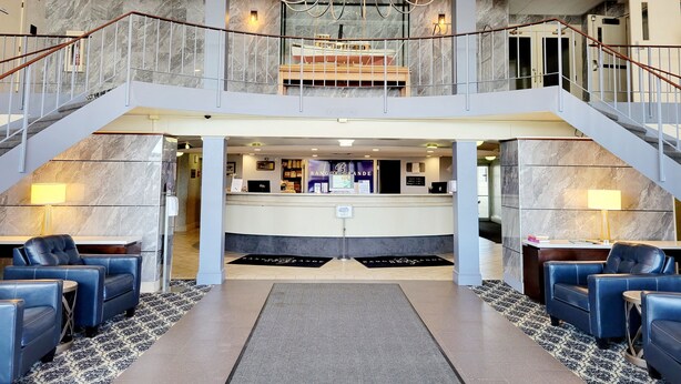A hotel lobby with a reception desk, a chandelier, and a staircase. - Bangor Grande (Bangor)