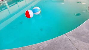 A swimming pool with two beach balls and lounge chairs in the background. - Bangor Grande (Bangor)