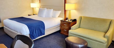 Una camera d'albergo con un letto, una scrivania, una sedia e un poggiapiedi.