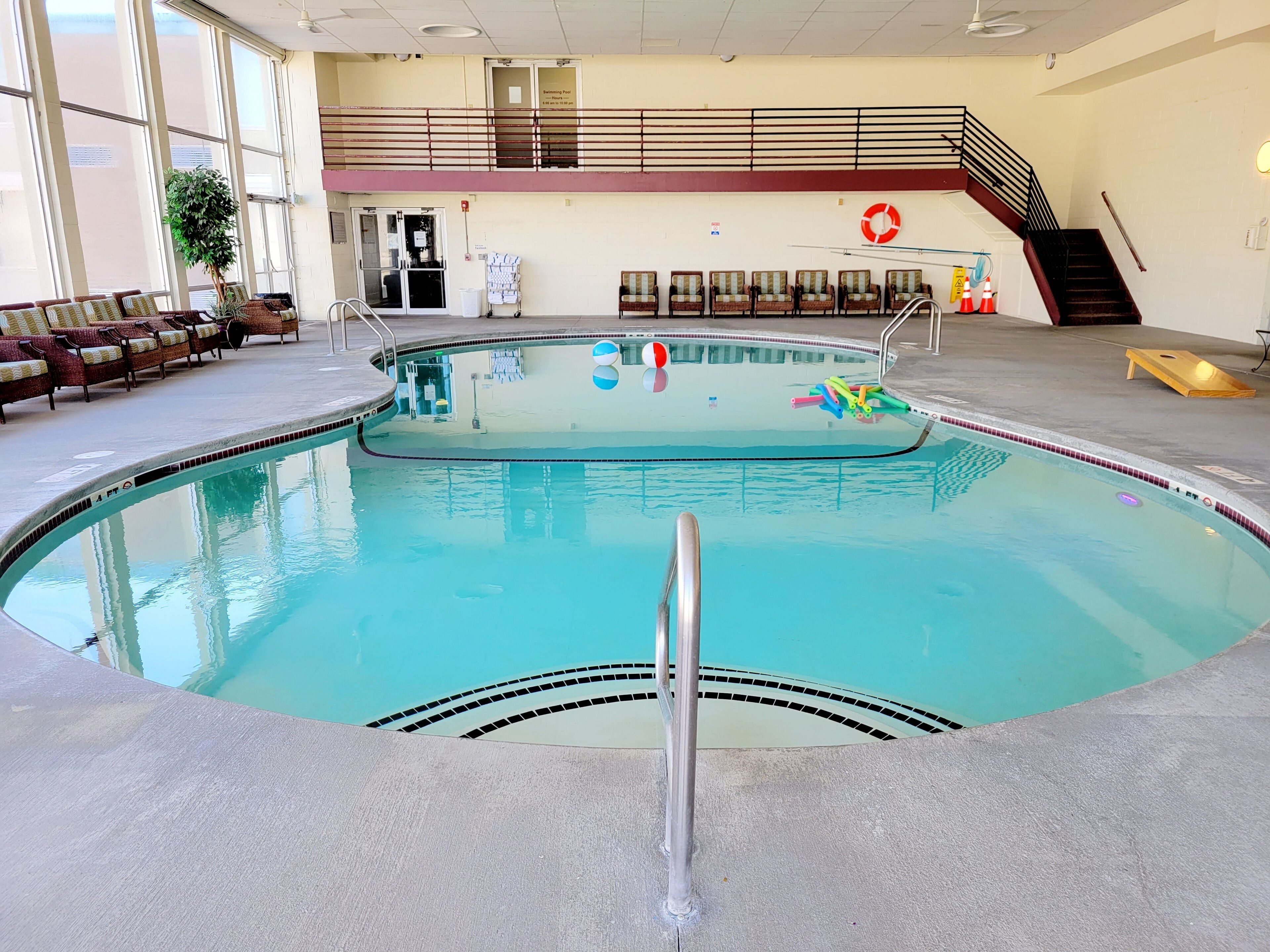 Ein Hallenbad mit Rettungsboje, Stühlen und einer Treppe.