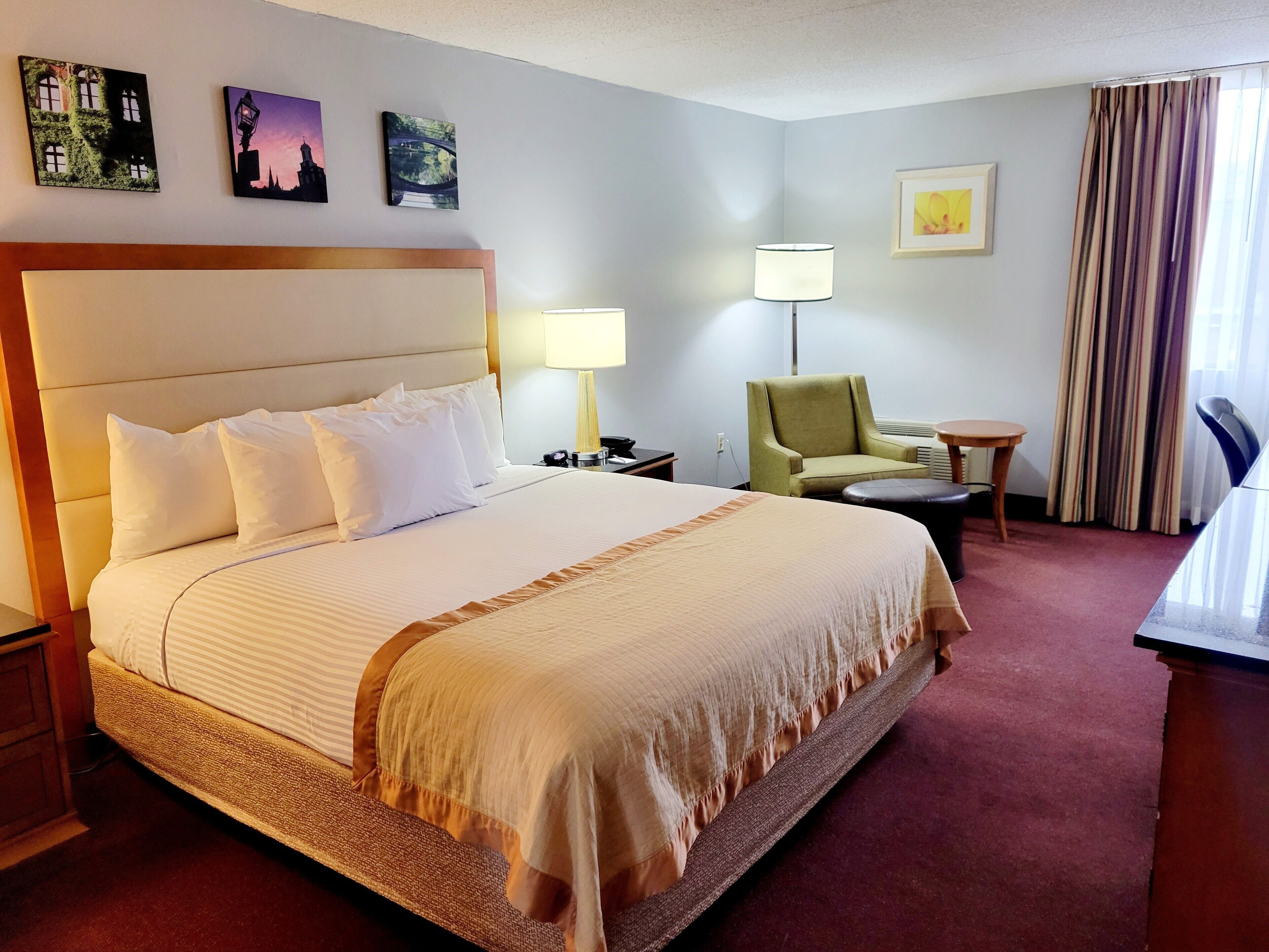 Een hotelkamer met een groot bed, een stoel, een bureau en een lamp.