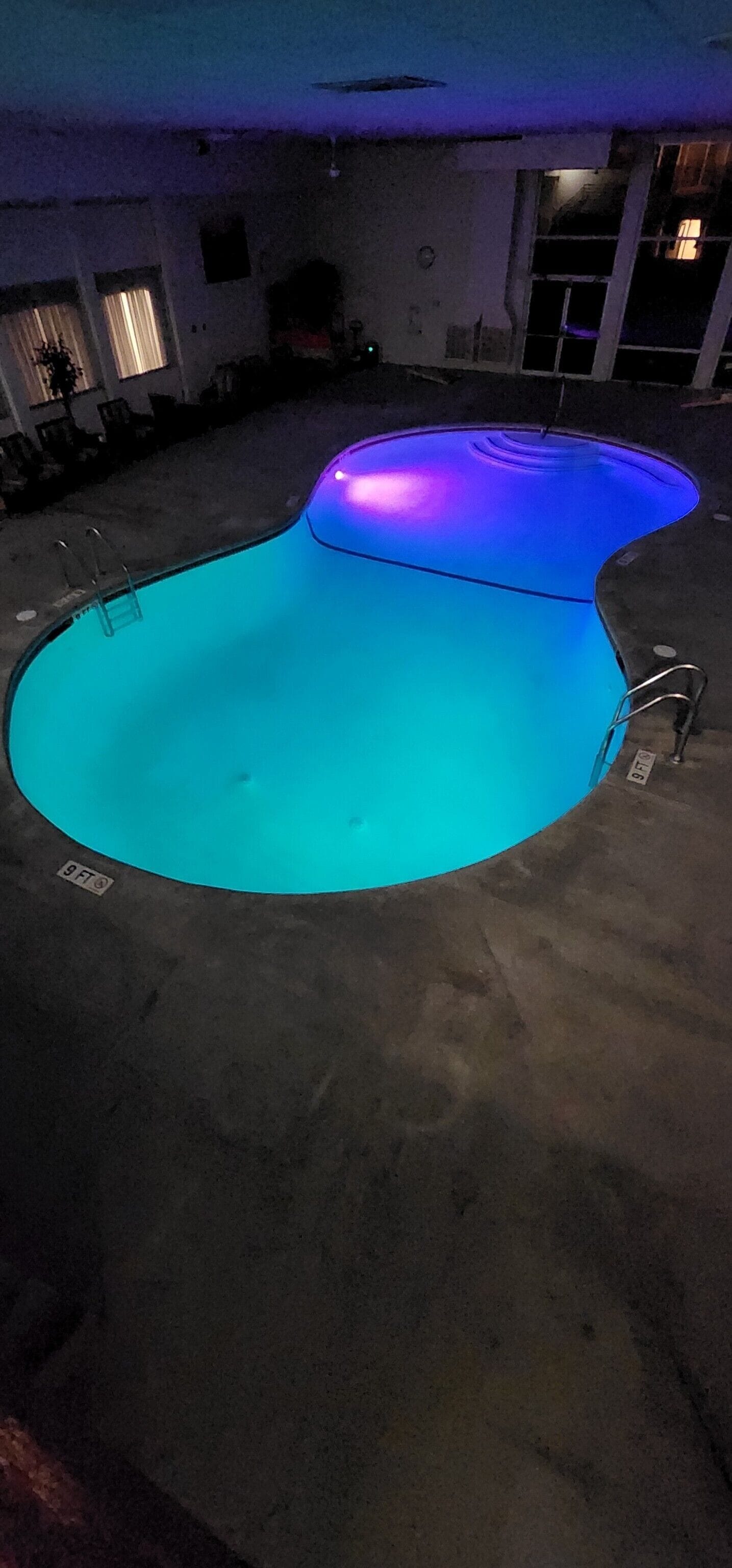 Une piscine intérieure au design incurvé, avec une échelle sur l’un des côtés.