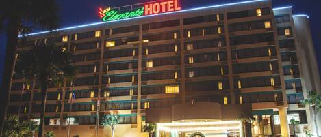 A multi-story hotel with a prominent sign reading "Elegance HOTEL" and a well-lit entrance.