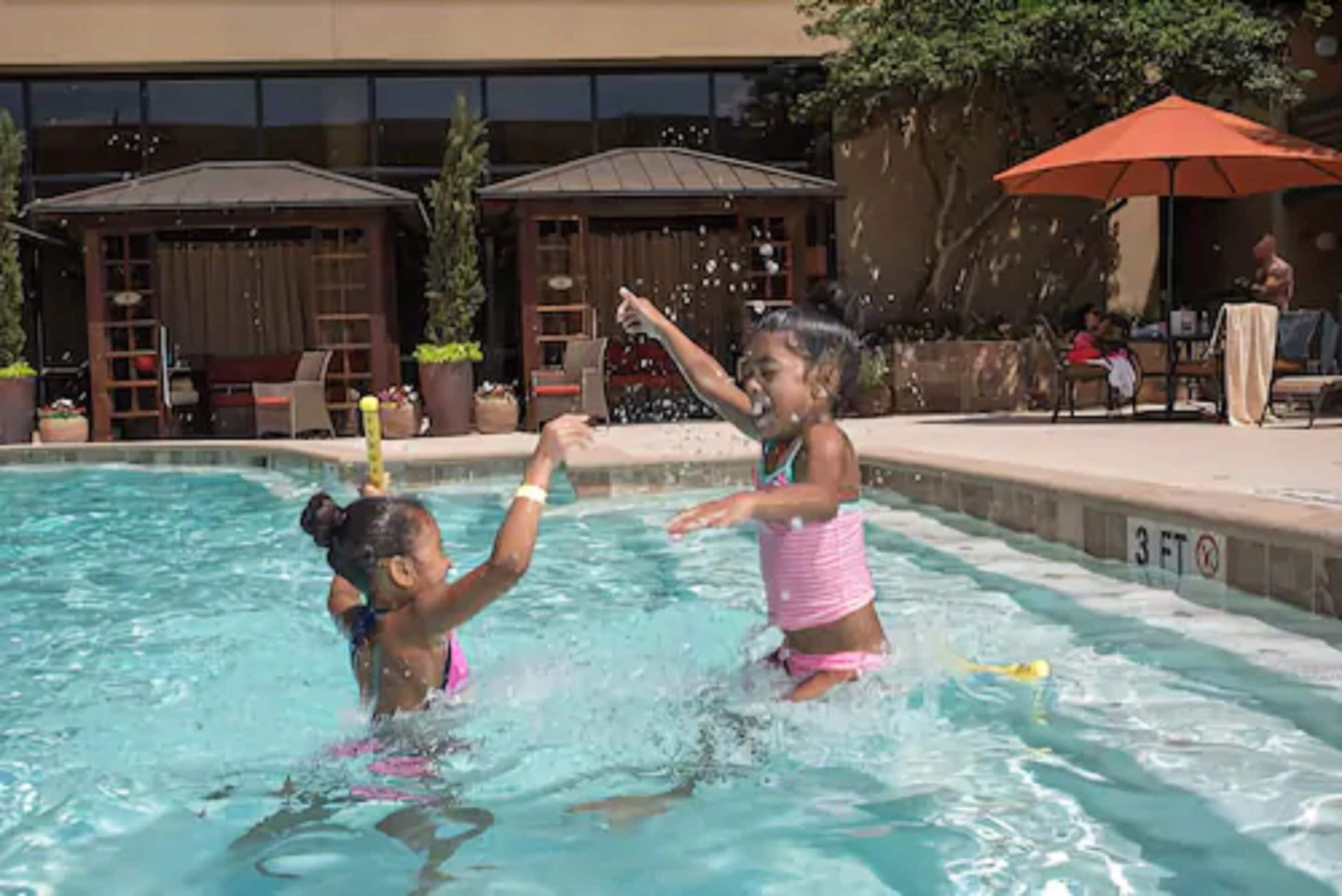 A swimming pool area with lounge chairs and umbrellas.