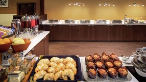 A buffet with various food items including croissants, muffins, and a fruit bowl.