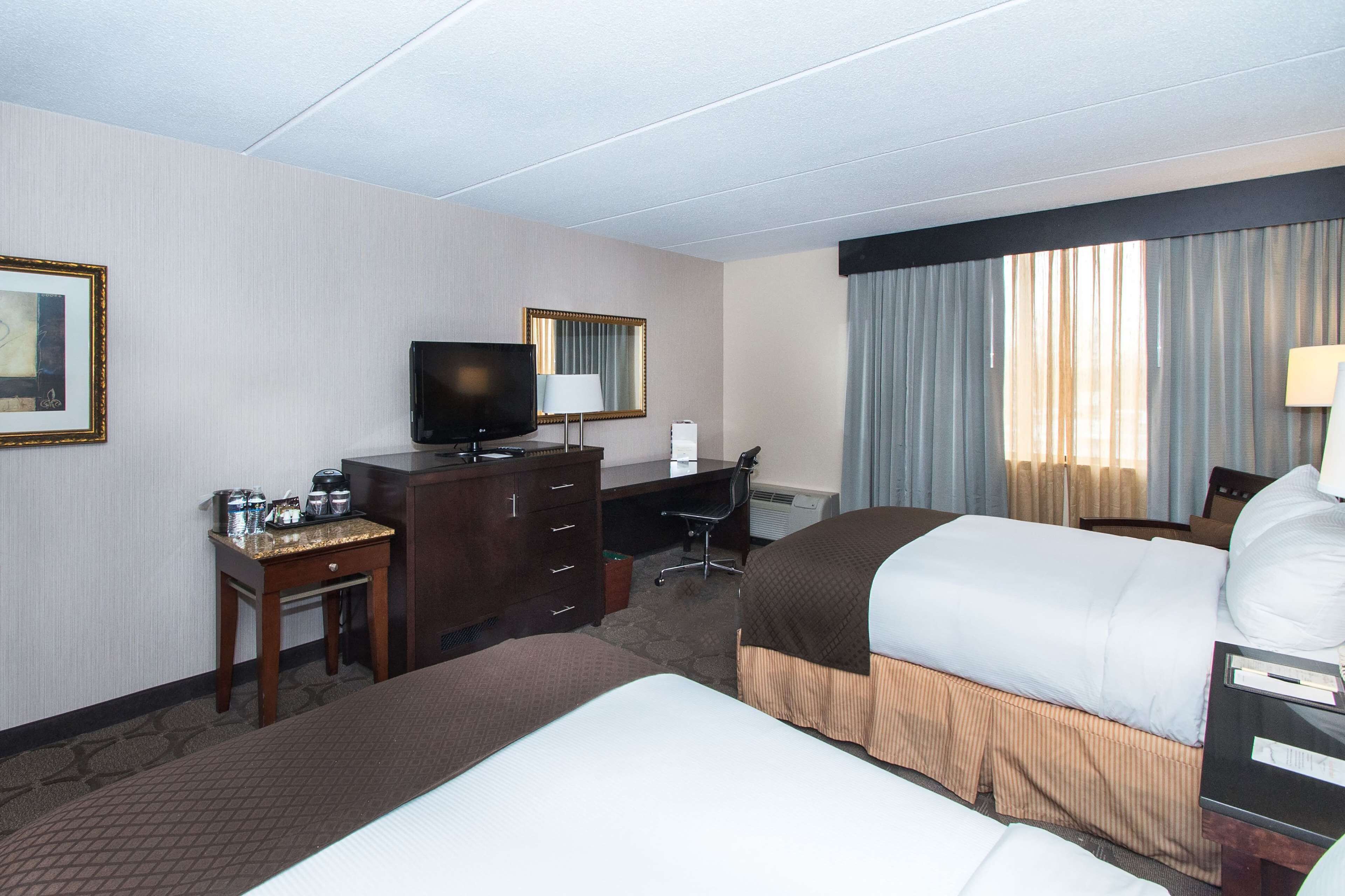 A hotel room with a bed, a desk, a television, a chair, and a window with curtains.