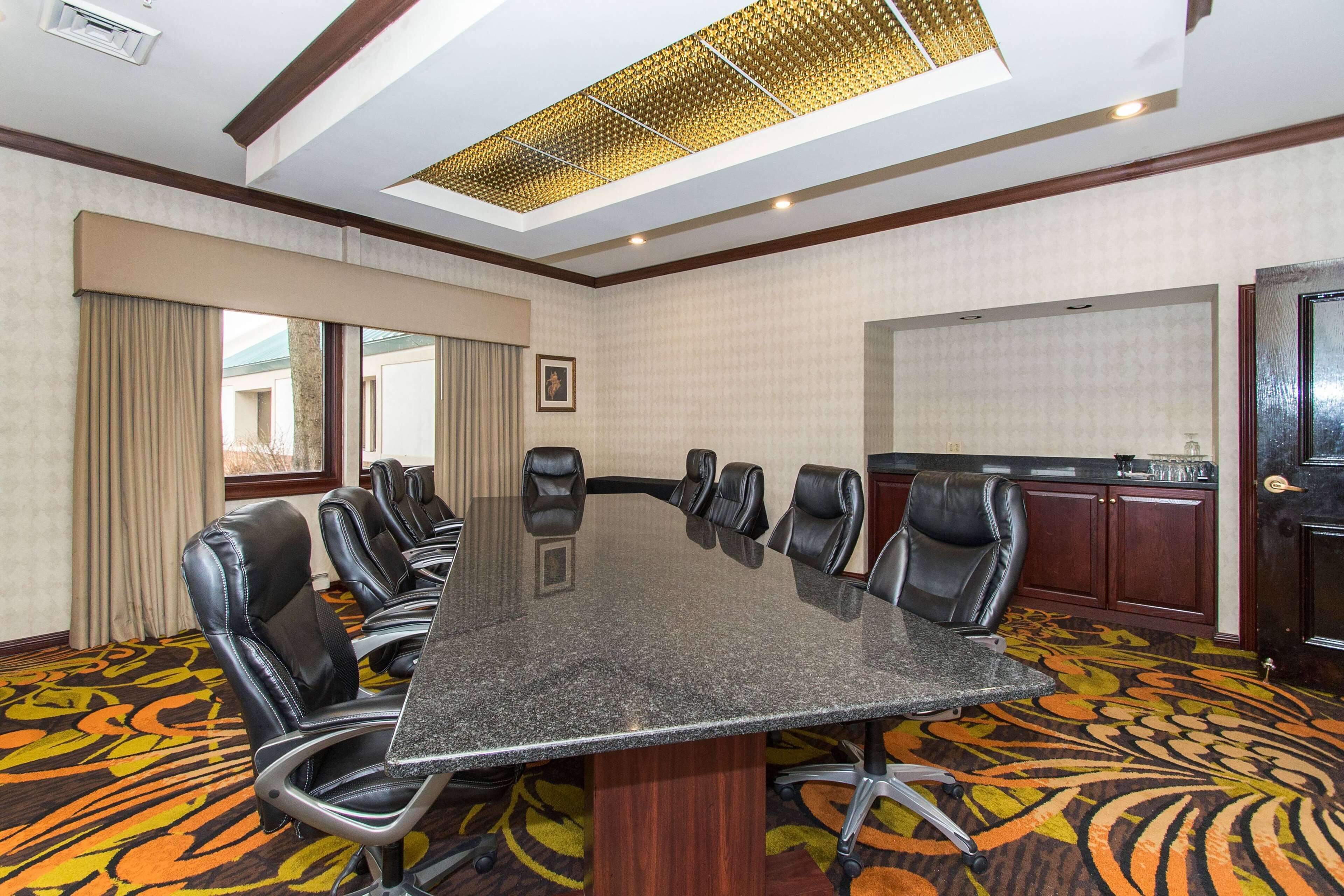 Une salle de conférence dotée d’une grande table, de fauteuils en cuir, d’un sol recouvert de moquette et offrant une vue par une fenêtre.