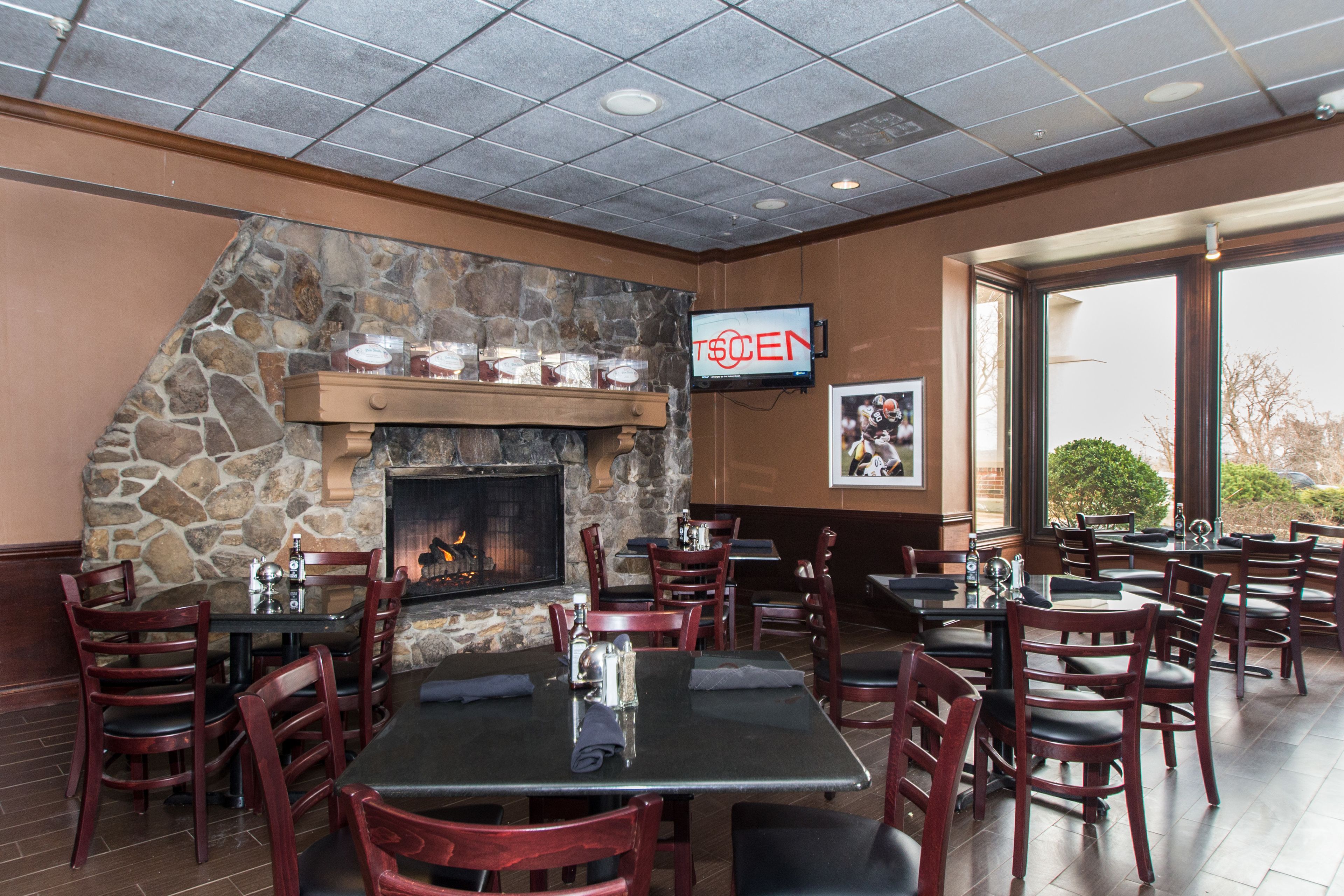 A restaurant with stone walls, a fireplace, and outdoor seating.