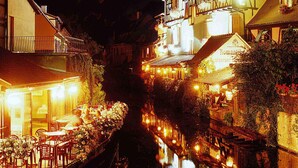 Un restaurante junto al río con terraza y ventanas iluminadas.
