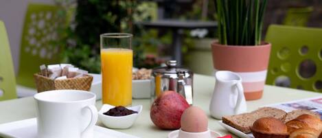 Una preparación para el desayuno con una taza de café, jugo, cruasanes y un muffin sobre una mesa.