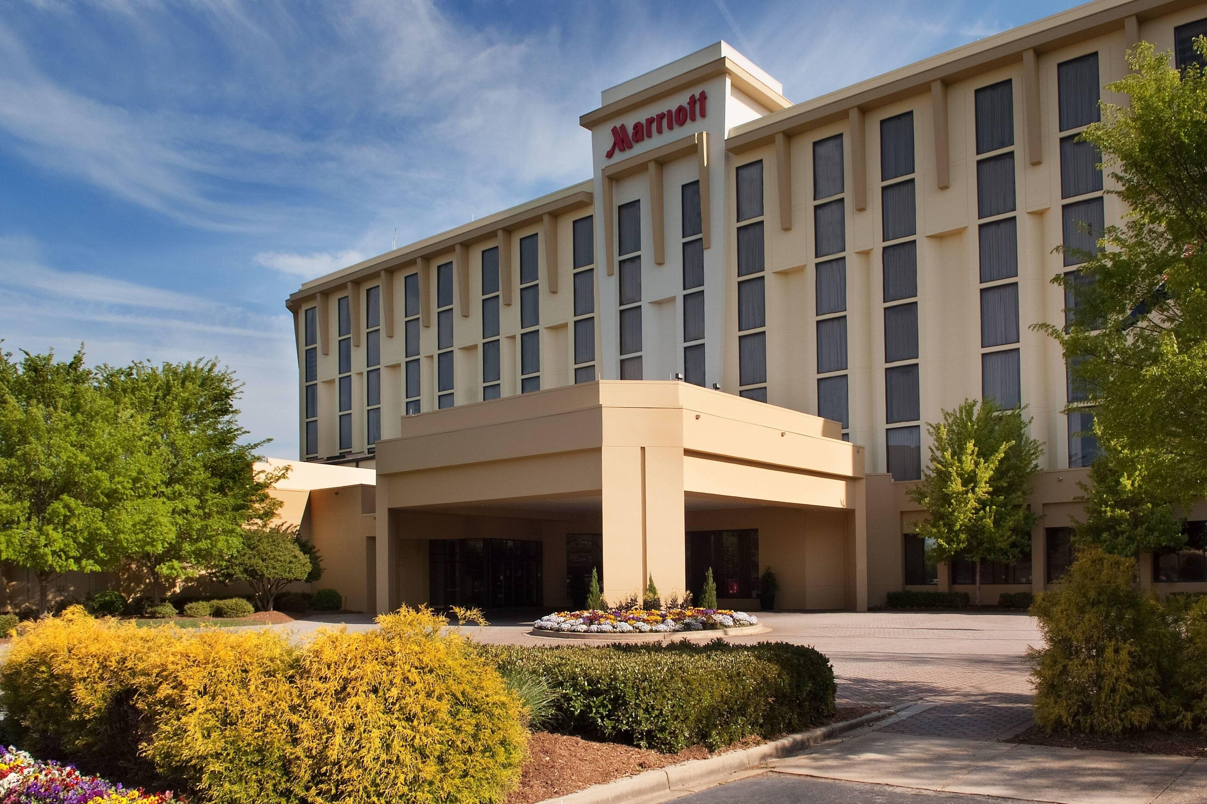 A Marriott hotel with a modern facade, a central entrance, and landscaped gardens.