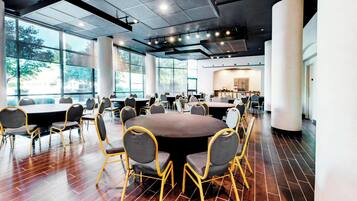 Una amplia sala de conferencias con mesas y sillas redondas, ventanas grandes y un diseño moderno de techo.