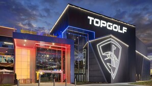 A modern building with a large illuminated logo reading "TOPGOLF" on the facade.