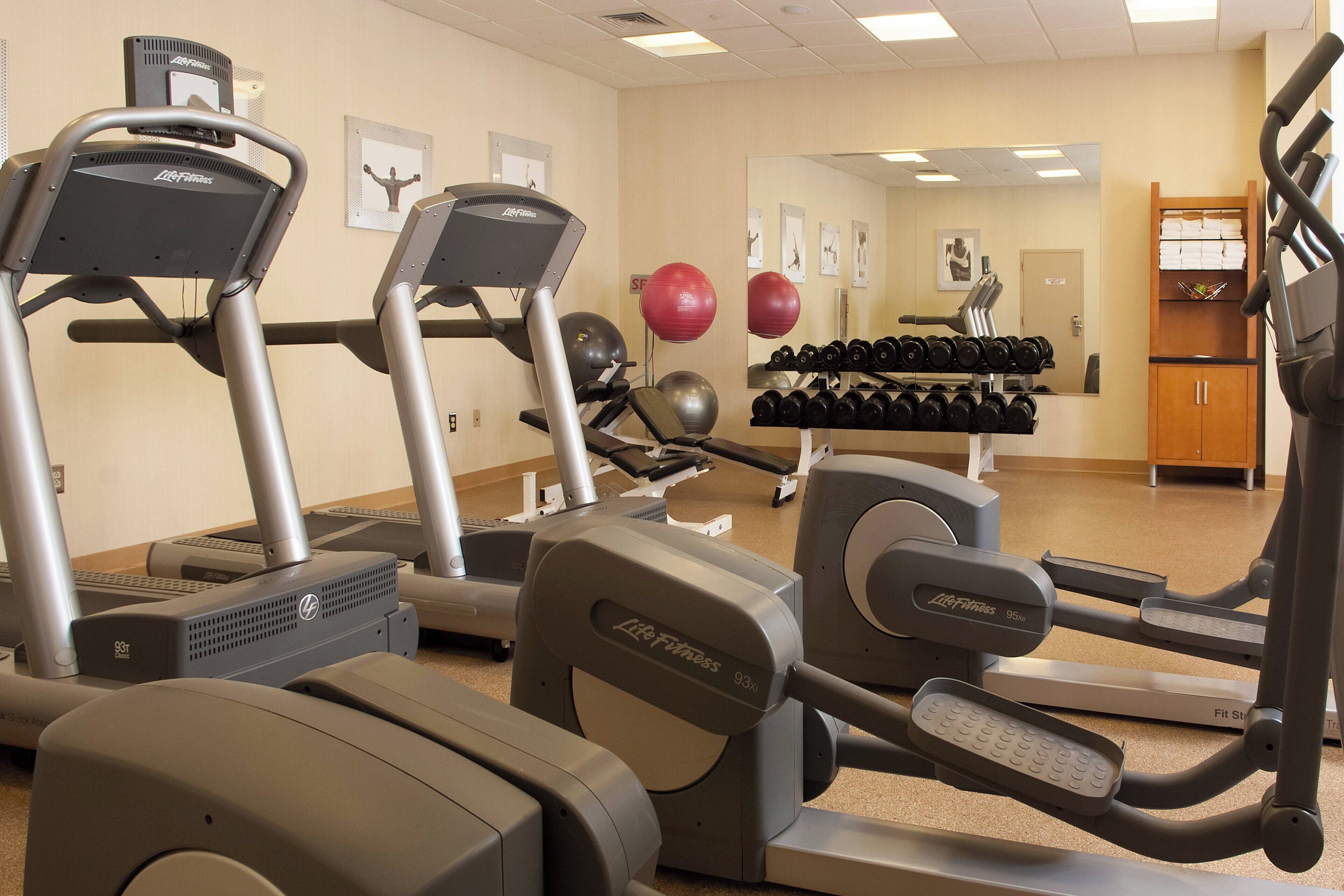 Un gimnasio con cintas de correr, elípticas y pesas sueltas.