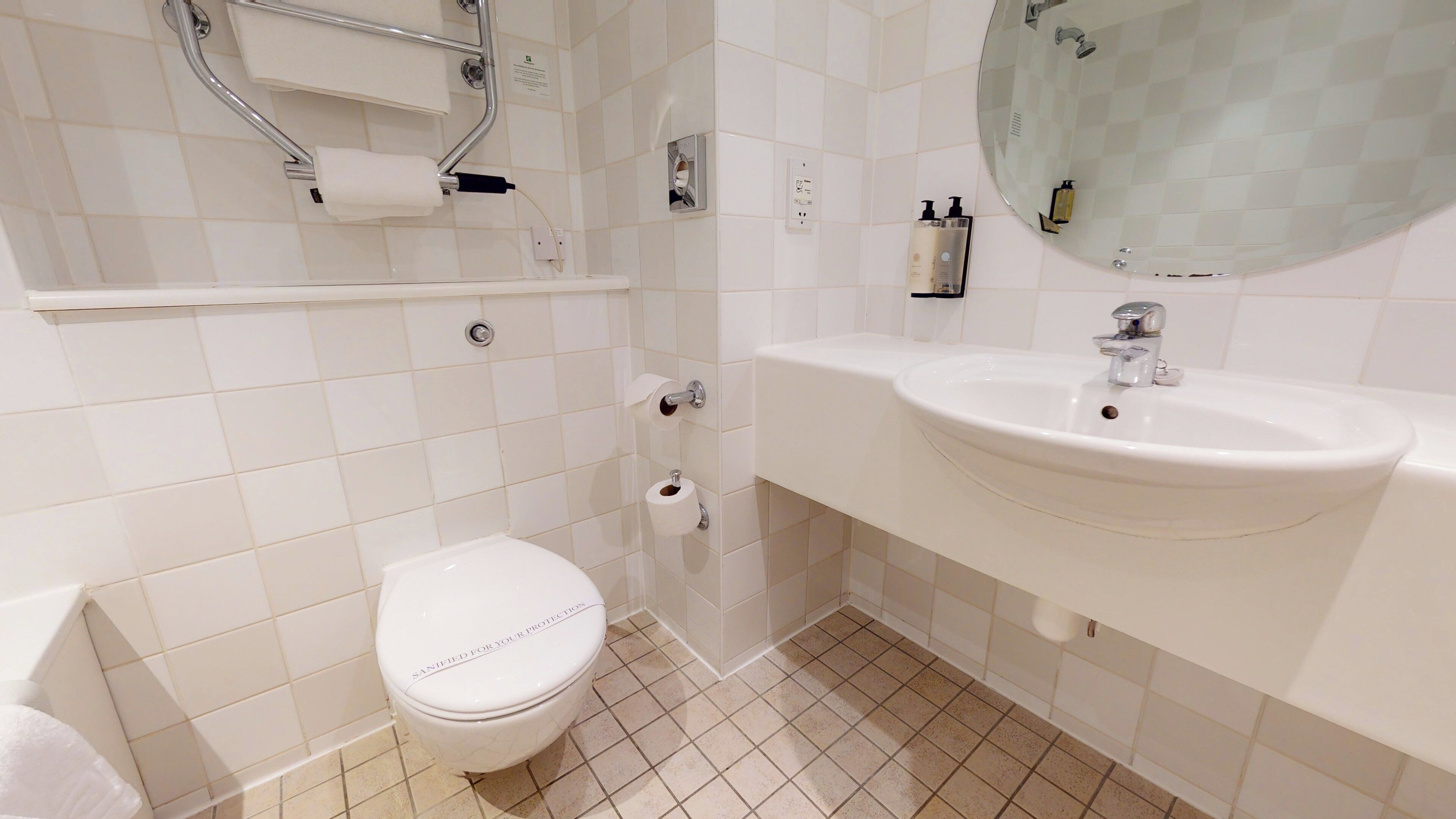 A modern bathroom with a toilet, sink, and mirror.