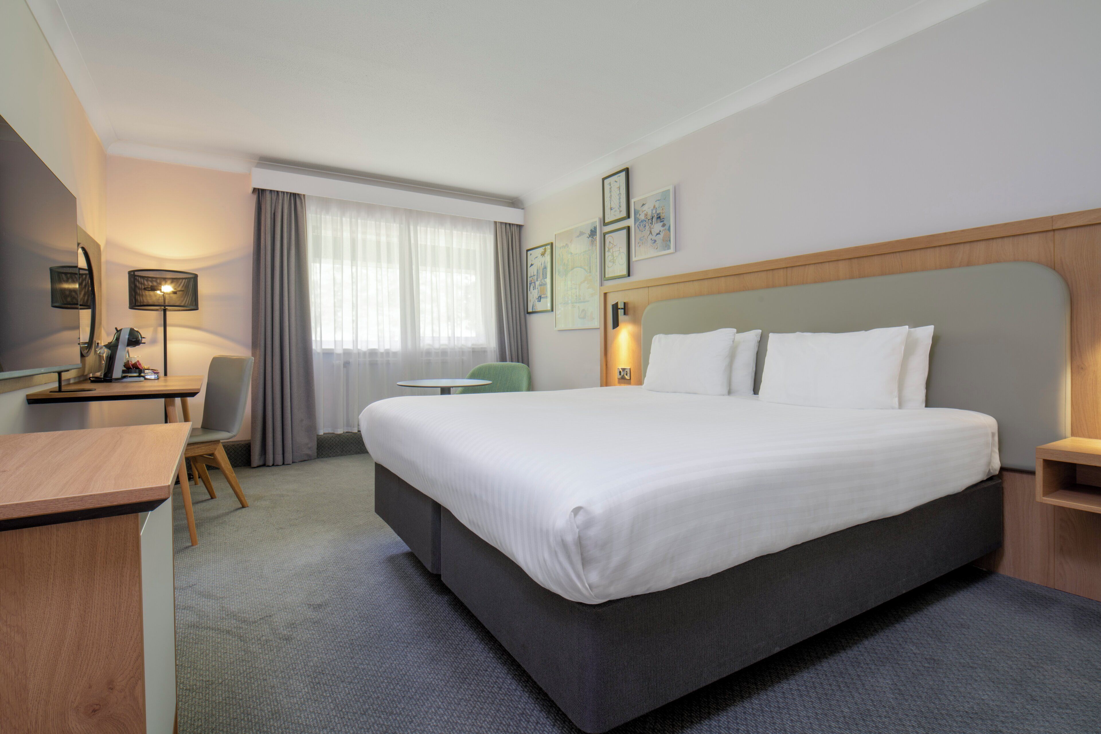 Una camera d'albergo con un letto grande, una scrivania, una sedia e una finestra con tende.