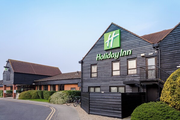 A Holiday Inn hotel with a dark facade, multiple windows, and a gated entrance.