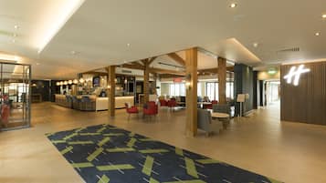 A spacious lobby with a central bar area, seating arrangements, and a patterned carpet.