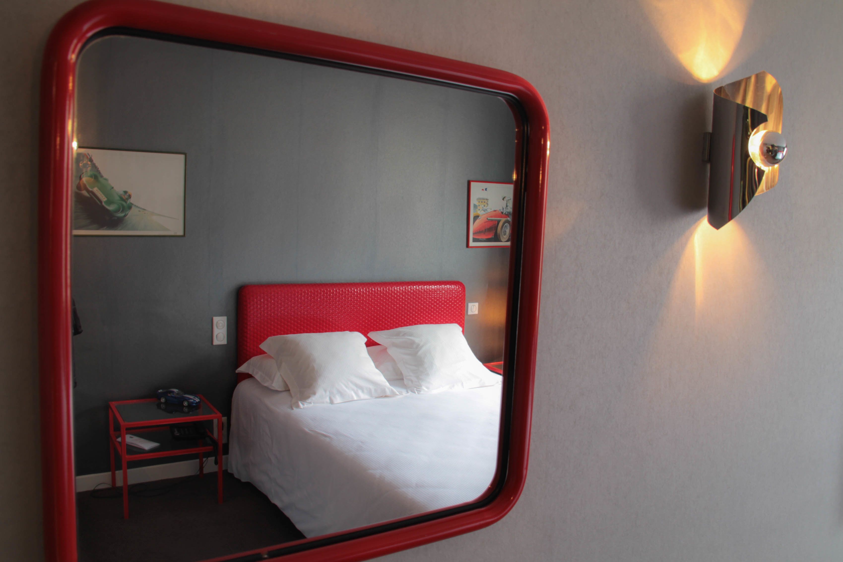 Een hotelkamer met een bed, een nachtkastje, een wandlamp en twee ingekaderde foto's.
