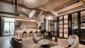A modern lounge area with a bar, seating arrangements, and a wine display. - Corinthia Palace Malta (Attard)