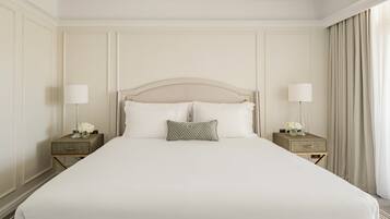 A large bed with a headboard, two bedside tables with lamps, and a window with curtains.