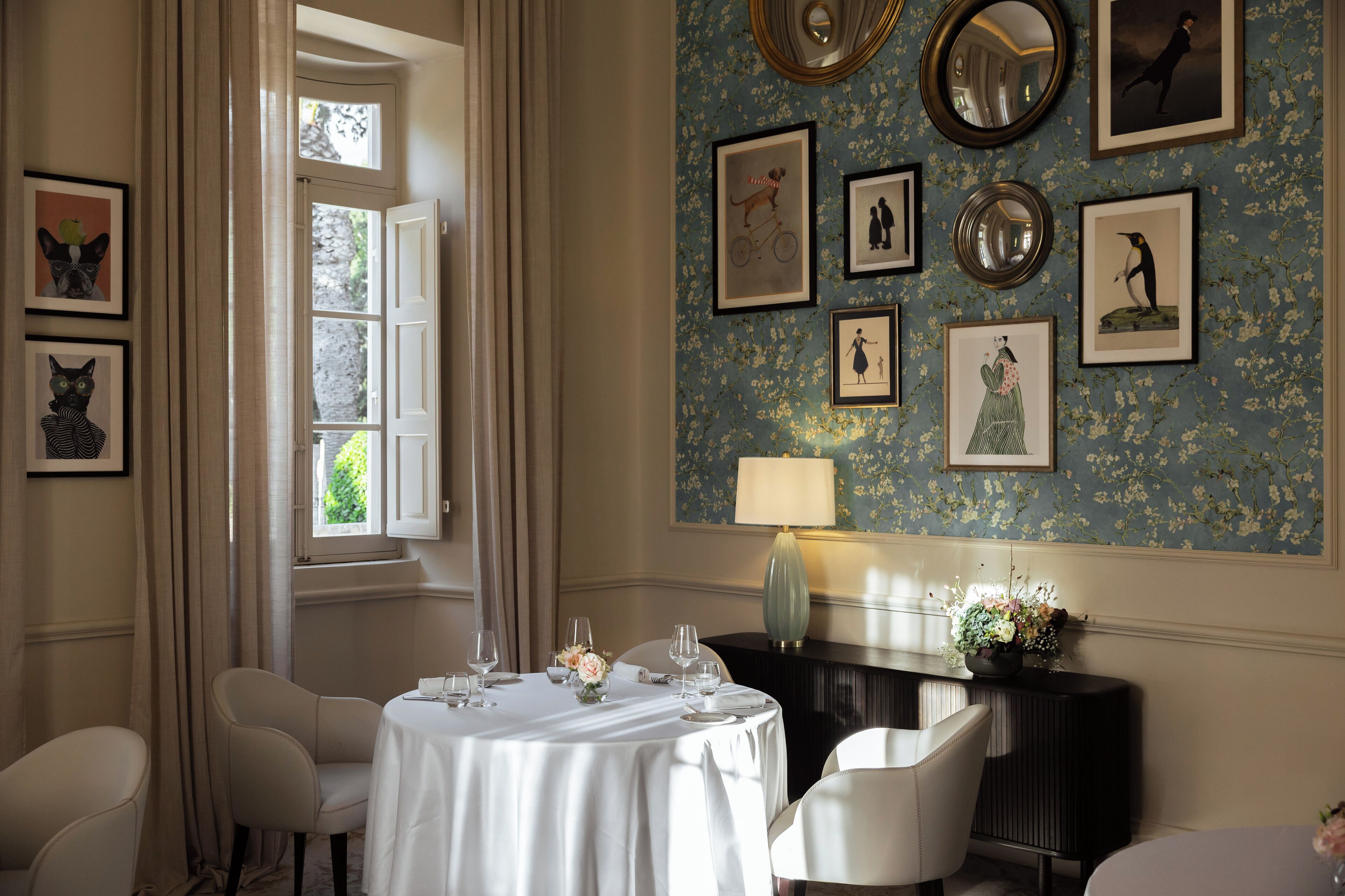 A dining area with a round table set for four, a black console table, and a wall adorned with framed artwork.