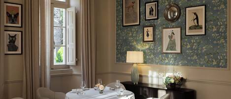 A dining area with a round table set for four, a black console table, and a wall adorned with framed artwork.