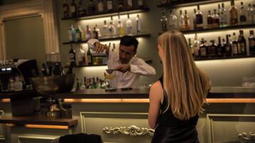 A bar area with a bartender preparing a drink, shelves of liquor bottles, and a bar counter.
