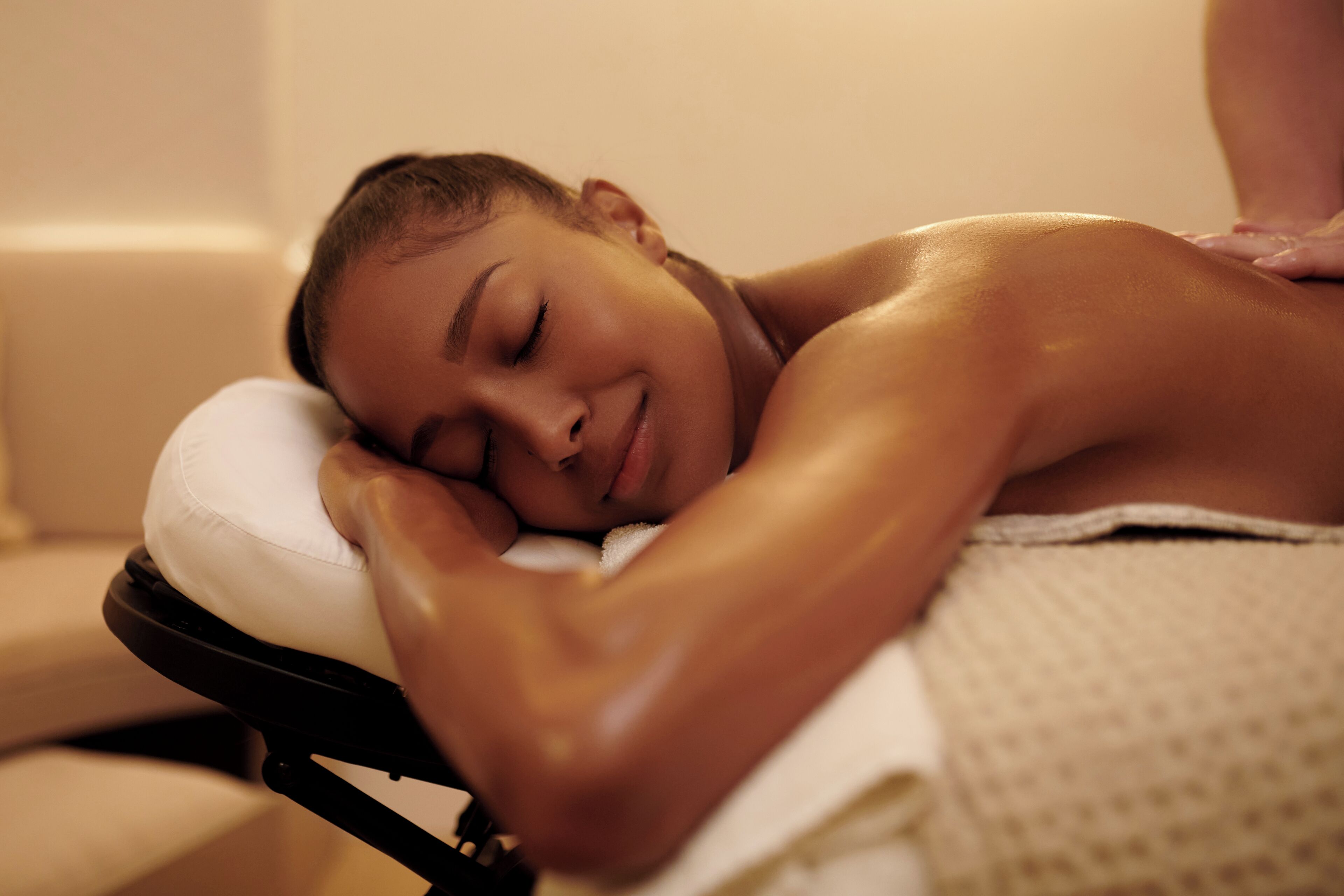 A person lying on a massage table with a white cushion, receiving a back massage.