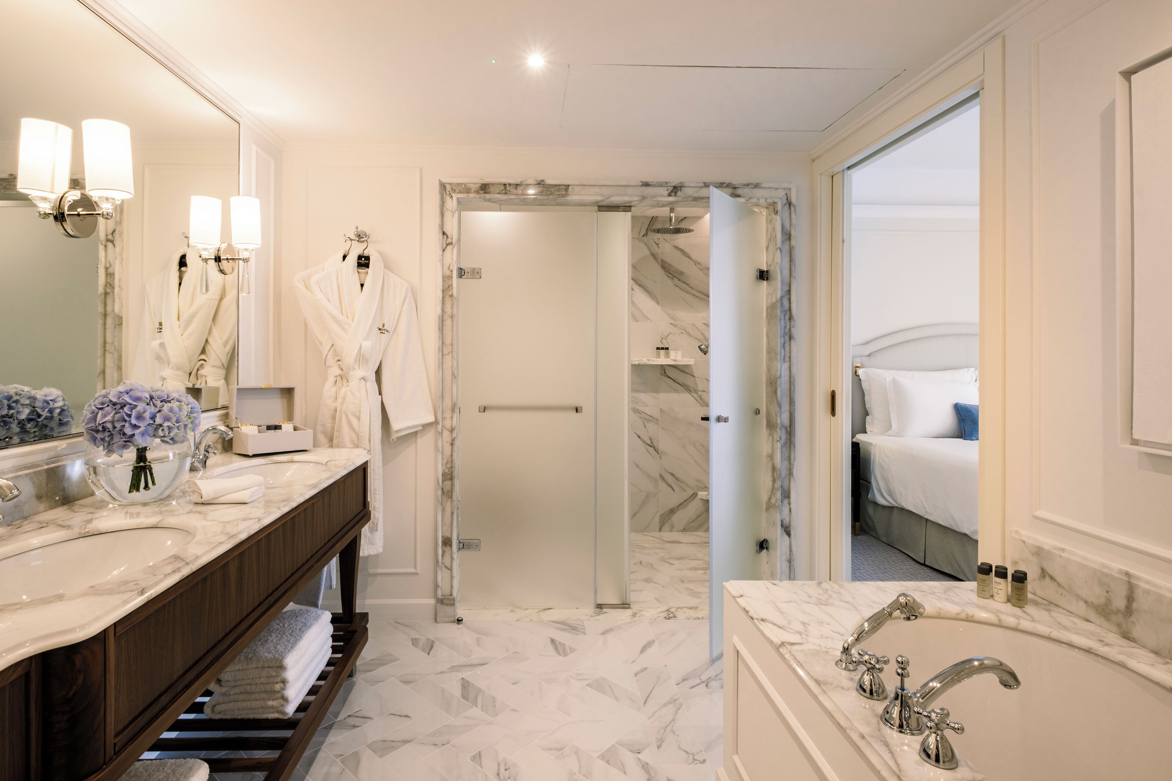 Un baño moderno con lavamanos de mármol, un espejo grande y una ducha a ras de suelo.