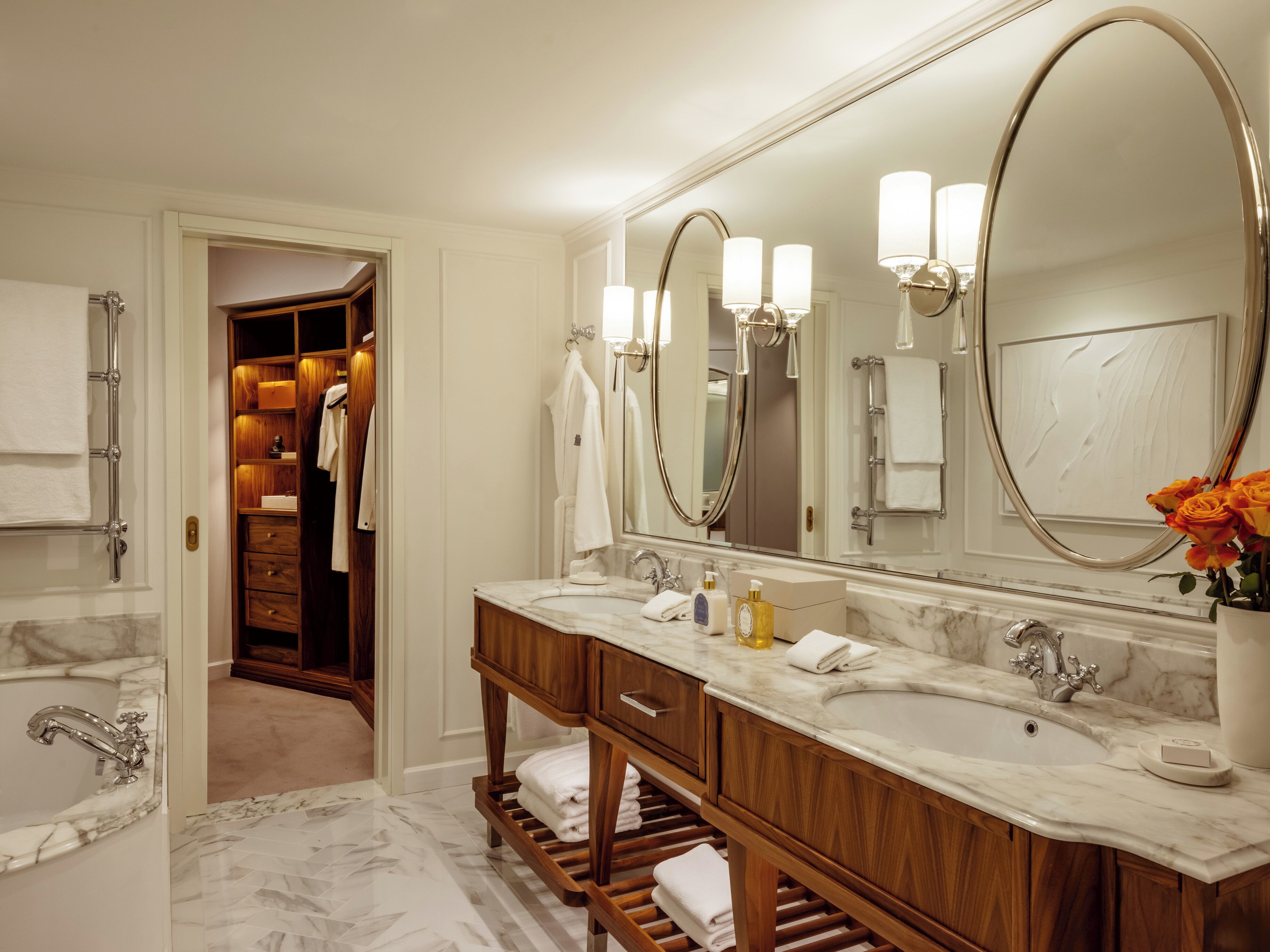 Un baño moderno con tocador de doble lavabo, un espejo grande y un vestidor.