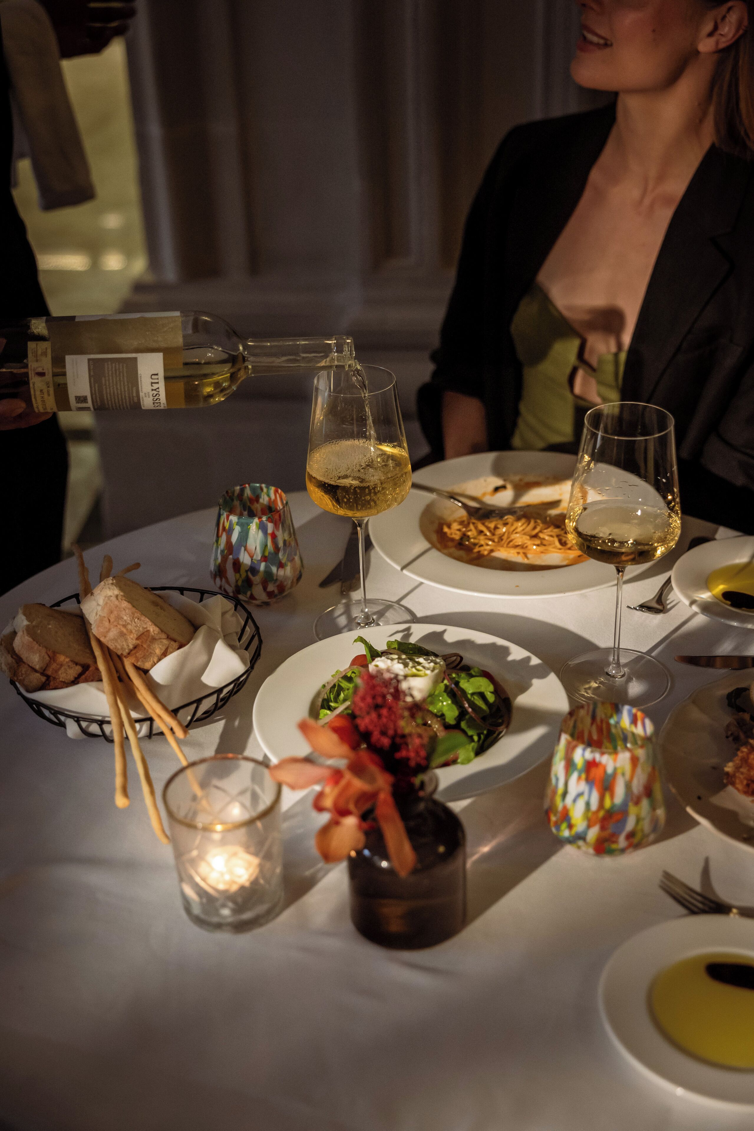 Una mesa de comedor con varios platos, copas de vino y una vela.