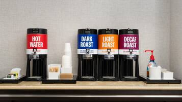 A coffee station with four dispensers labeled 'Hot Water,' 'Dark Roast,' 'Light Roast,' and 'Decaf Roast.'