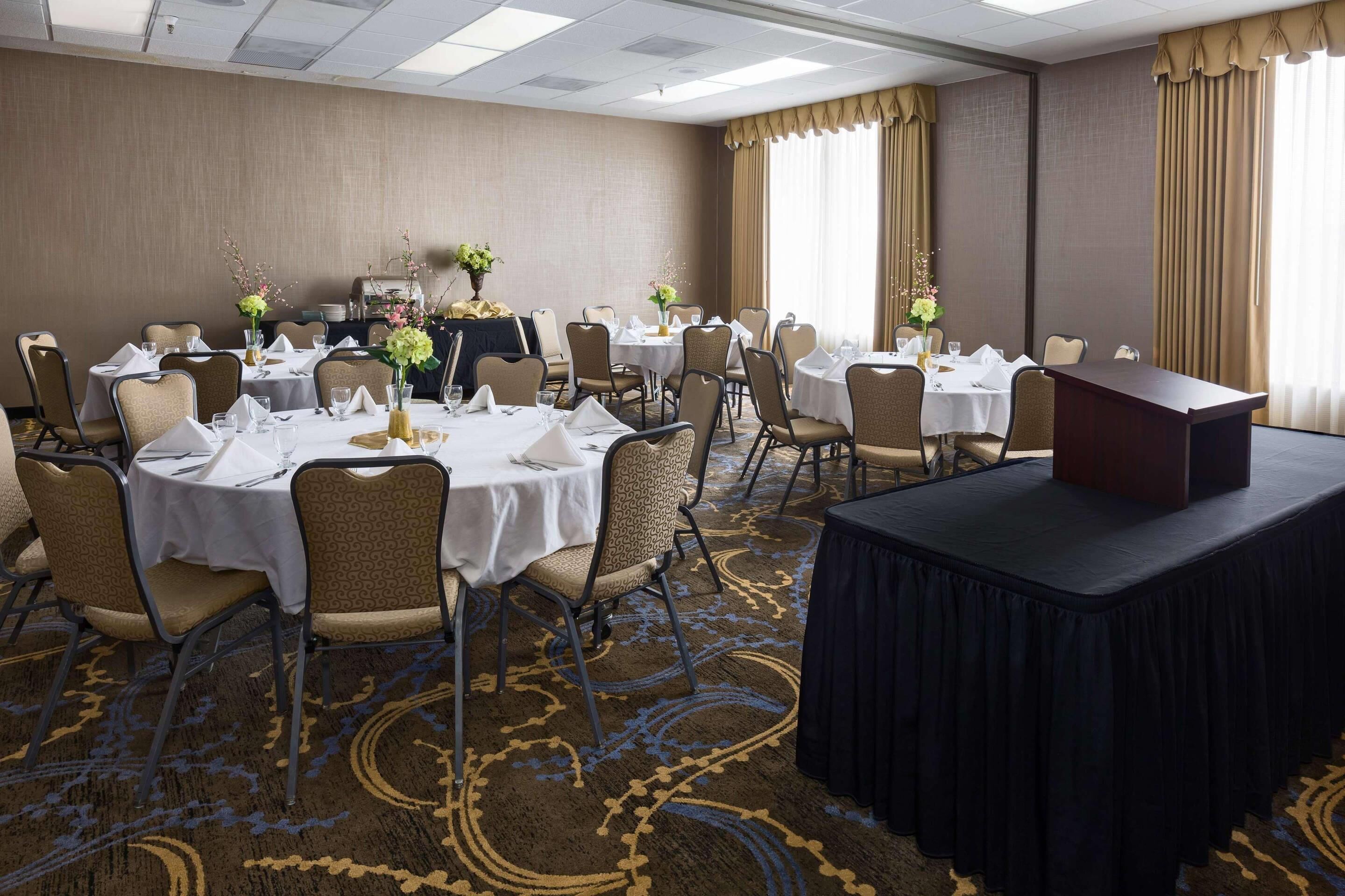 A conference room with round tables, chairs, and a podium.