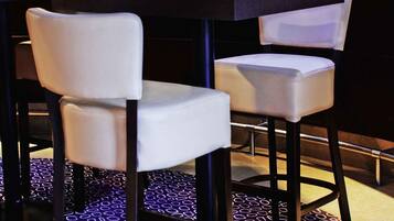 A restaurant interior with a dark floor, white cushioned chairs, and a black table.
