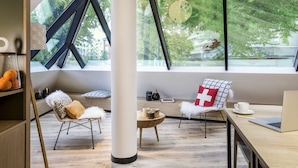 A modern room with a large window, a wooden table, two chairs, a laptop, and a cup. - Mercure Chambery Centre (Chambery)