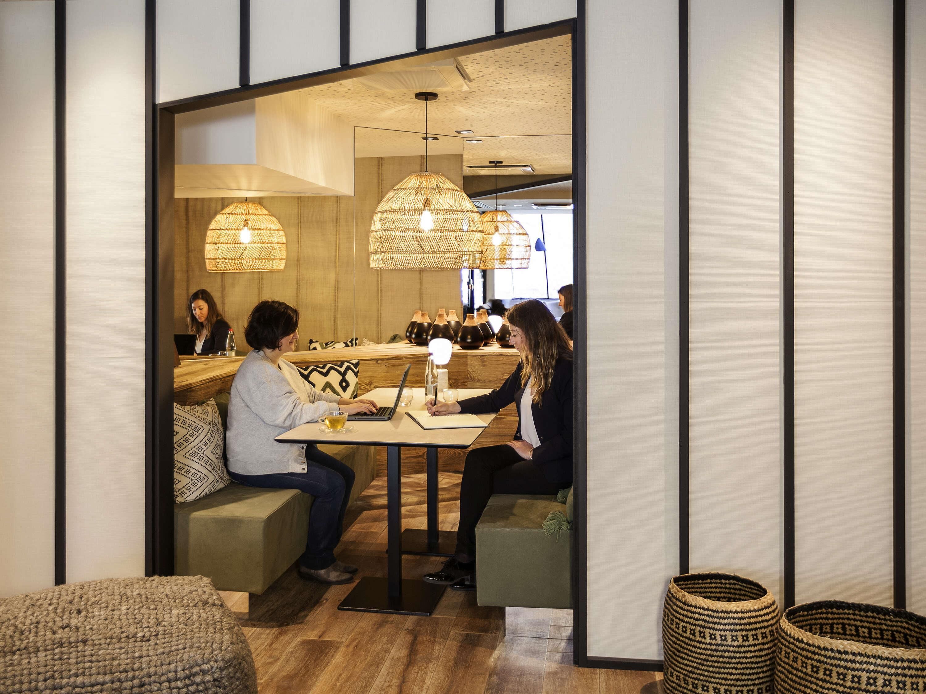 A modern interior with wooden flooring, a seating area with a table, and hanging lamps.