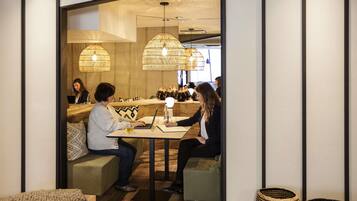 A modern interior with wooden flooring, a seating area with a table, and hanging lamps.