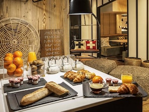 Un bufé de desayuno con pan, bollería y fruta.