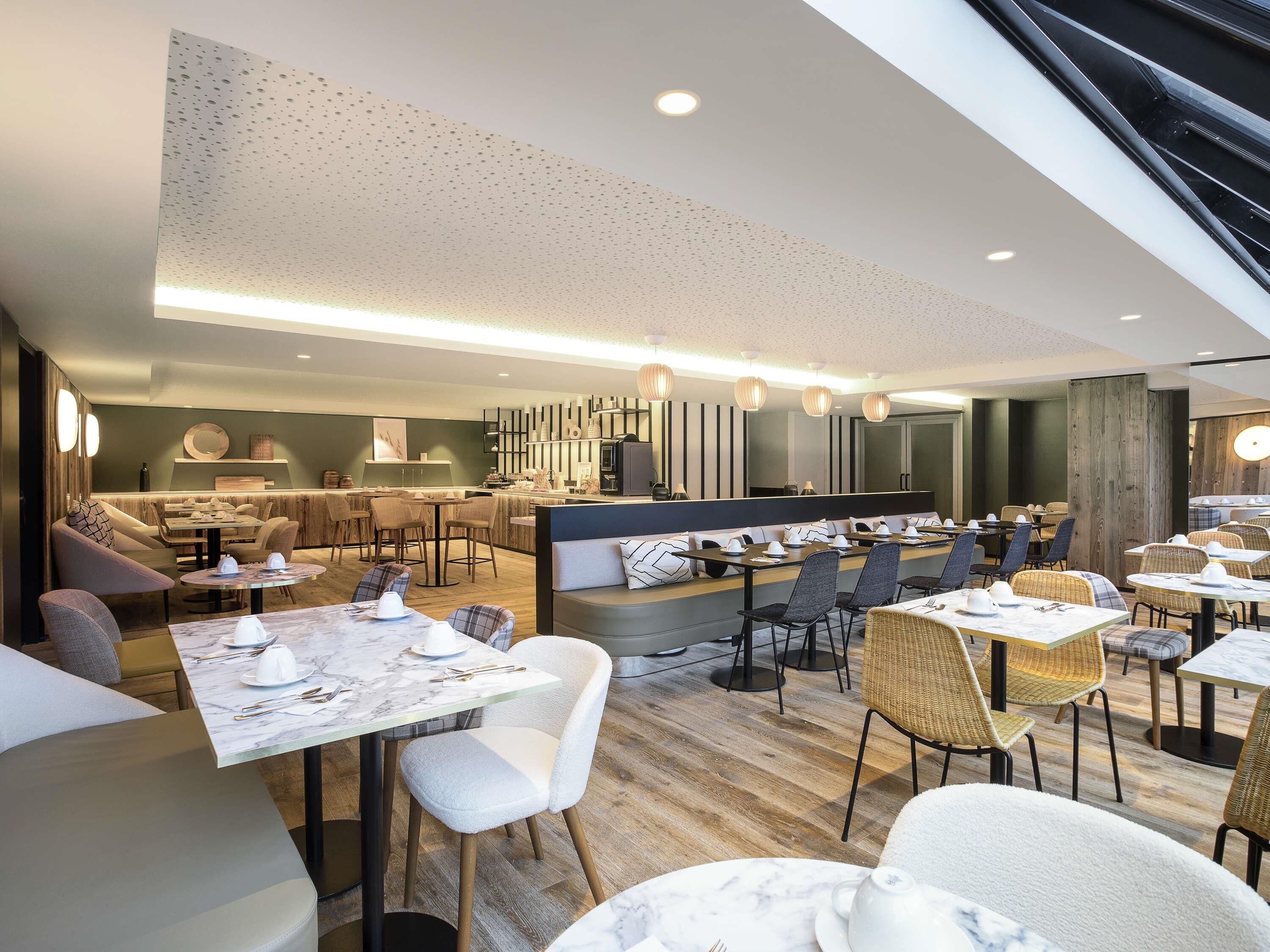 A modern restaurant with a bar area, seating arrangements, and a wooden floor.