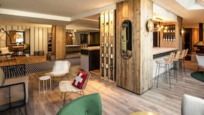 A modern hotel lobby with a bar area, seating arrangements, and a wooden accent wall. - Mercure Chambery Centre (Chambery)