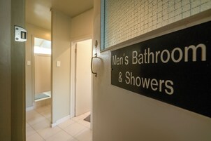 A men's bathroom sign with a tiled wall and a door leading to a bathroom.