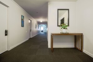 A hallway with a wooden console table, a mirror, and a door with a 'Please Do Not Disturb' sign. - Kiwi International Hotel (Auckland)