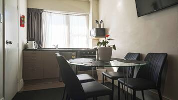 A compact kitchen with a microwave, stove, and a small dining area with a glass table and four chairs.