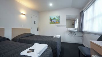 Una habitación de hotel con dos camas, un baño y un escritorio.